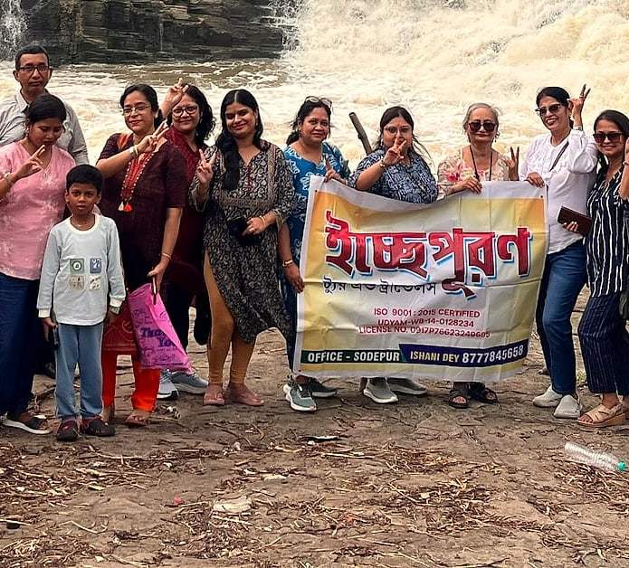 An ECHEPURON group holding the ইচ্ছেপূরণ banner on the rocks by a waterfall near Dhanbad