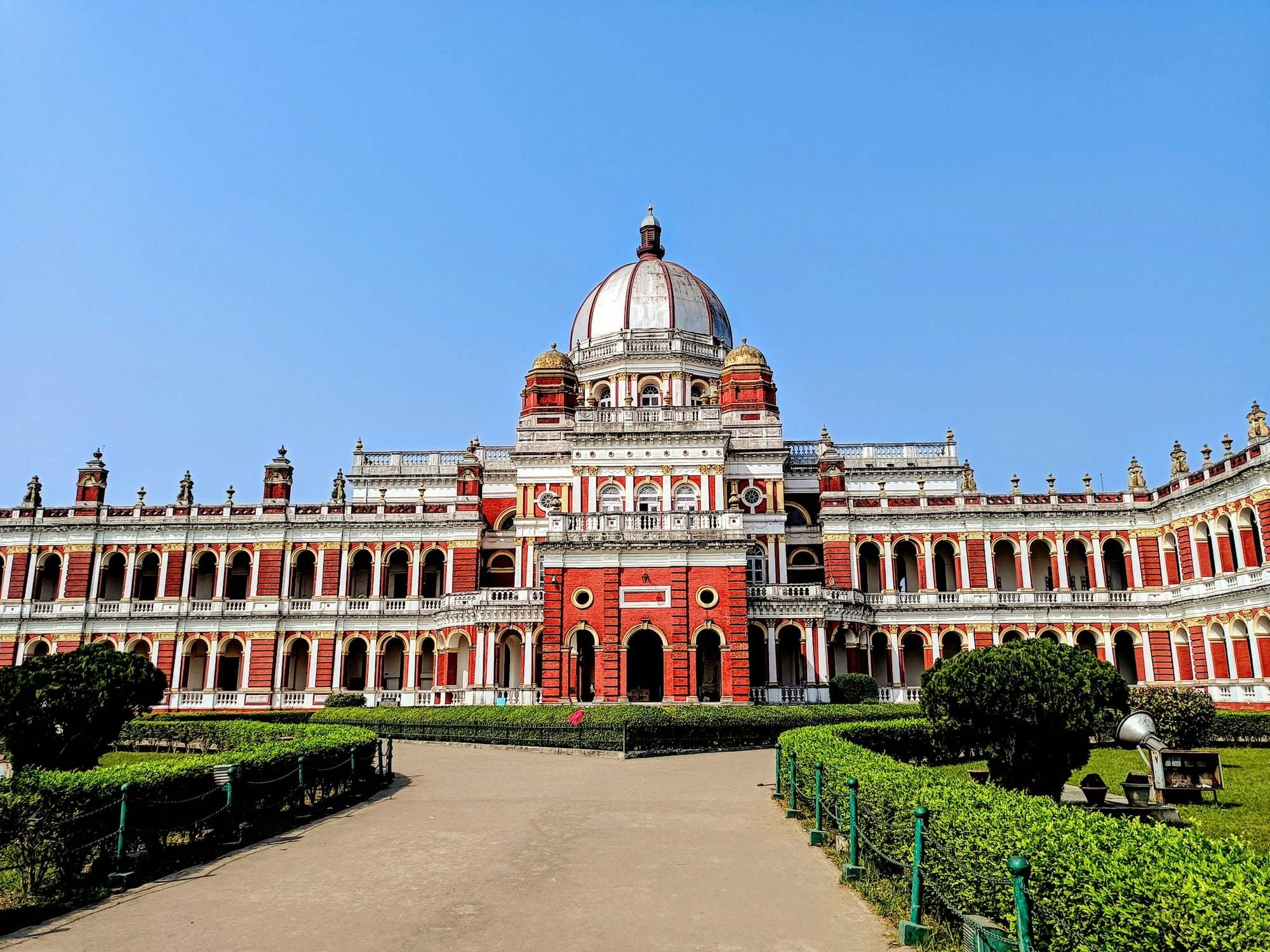 The red-and-cream Cooch Behar Palace and its central dome under a clear blue sky